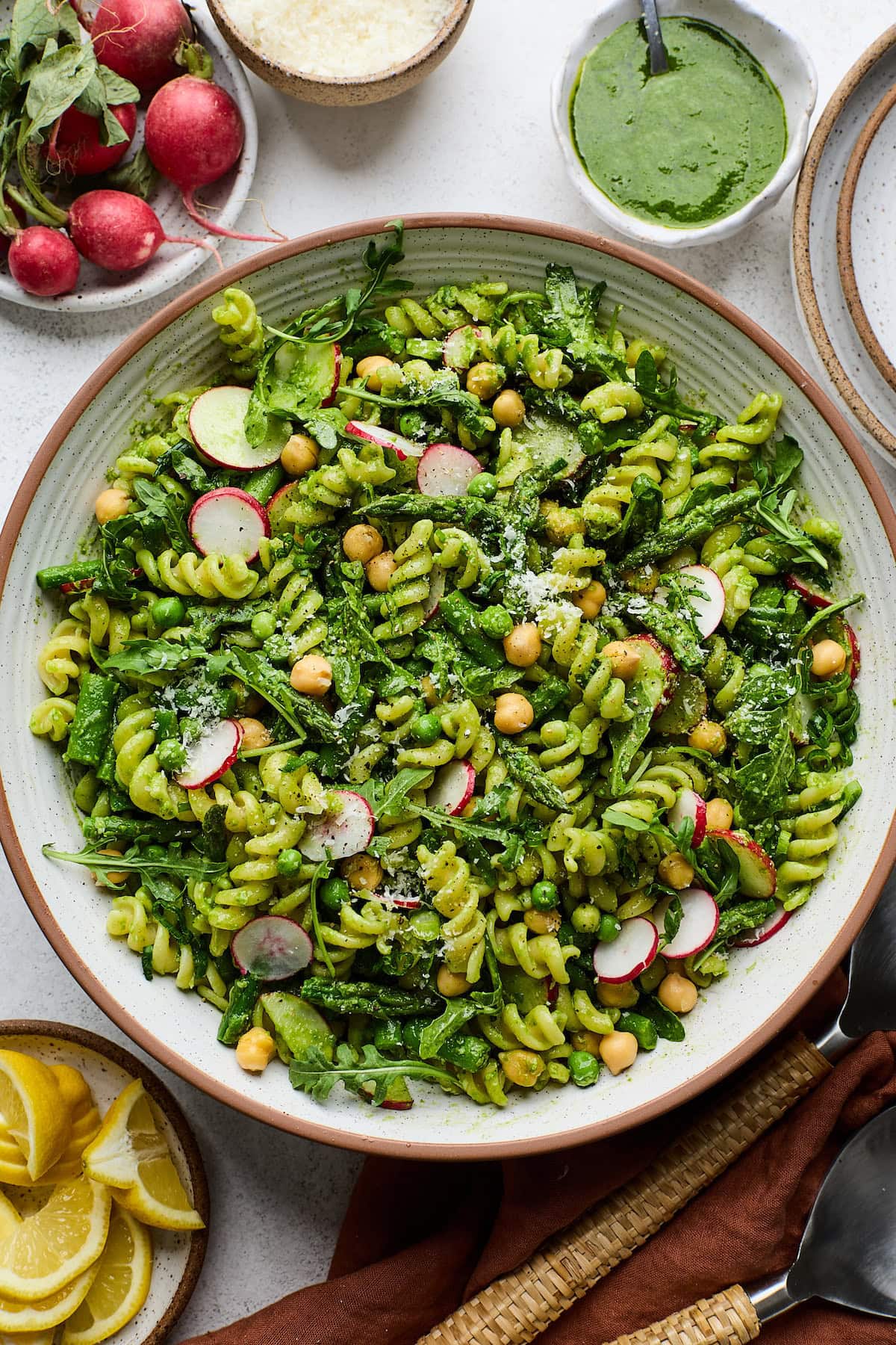 Pasta Salad with Asparagus, Chickpeas, Peas, Arugula, Radishes, Parmesan cheese and basil vinaigrette in bowl.