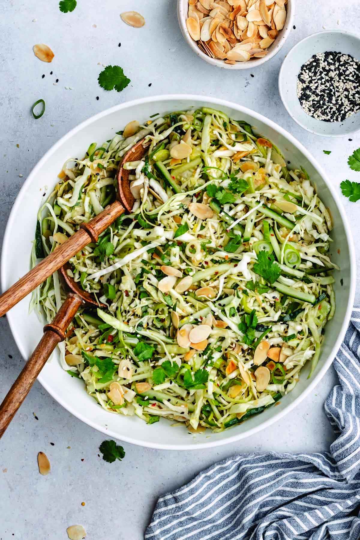 Sesame cabbage salad in bowl with wood salad servers.