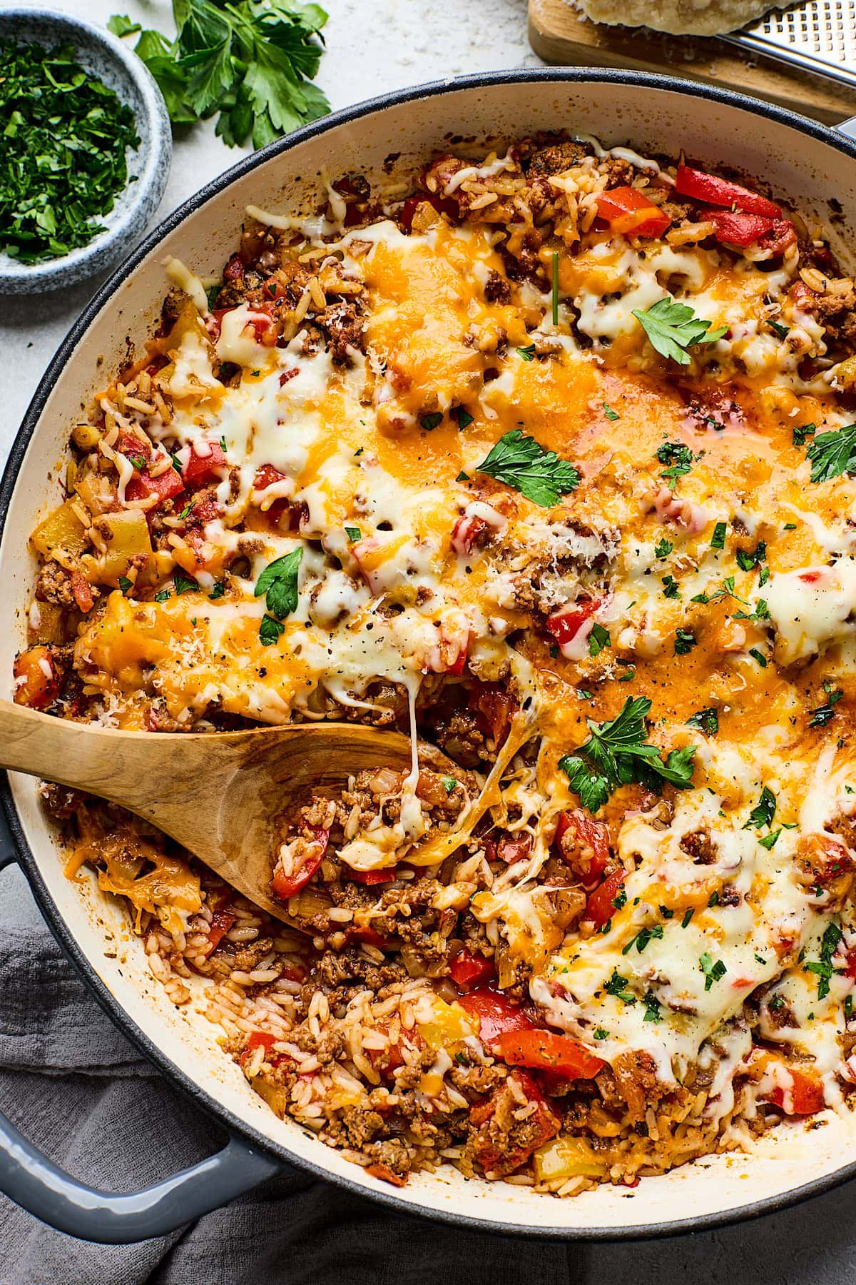 cheesy stuffed pepper skillet being served with a wooden spoon. 