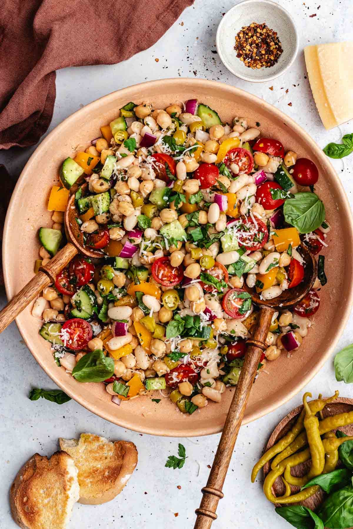 Italian bean salad in bowl with wood salad servers.