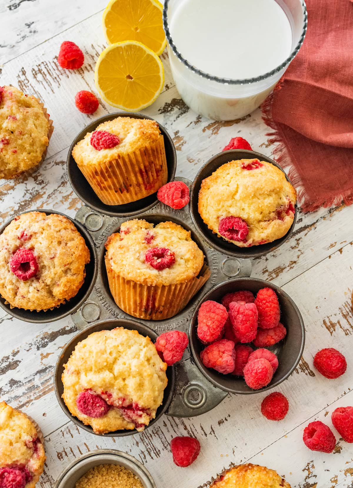 raspberry lemon ricotta muffins in muffin pan with fresh raspberries.