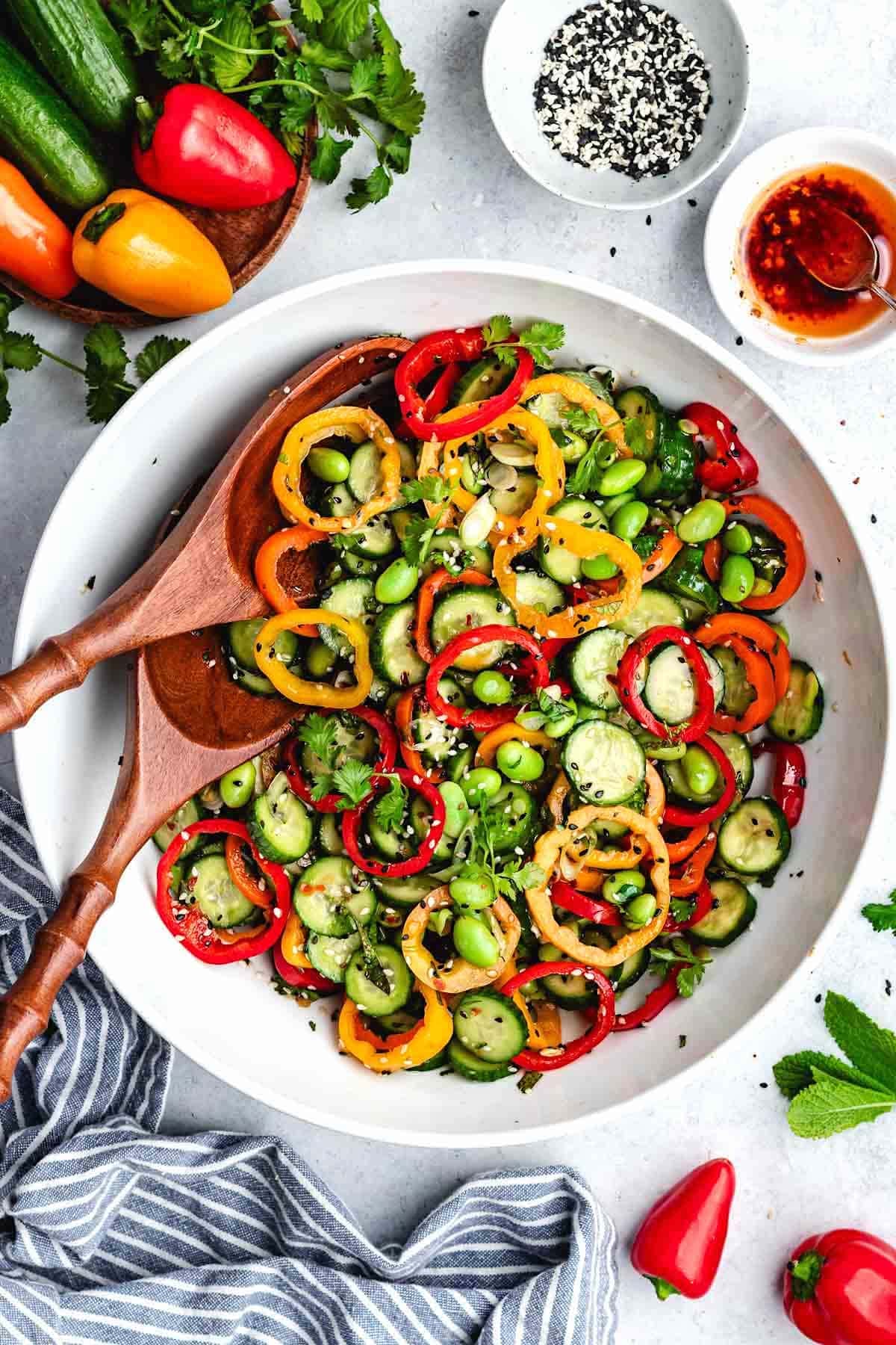 cucumber sweet pepper salad with edamame, fresh herbs, and everything but the bagel seasoning in bowl with salad servers.