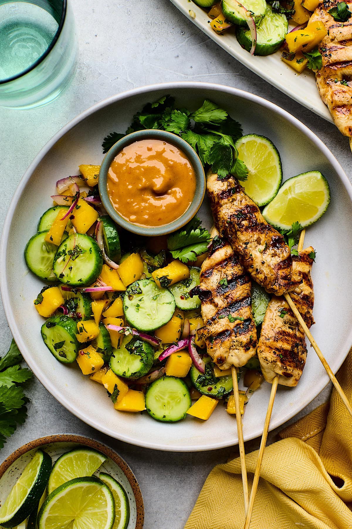 chicken satay with peanut sauce and cucumber mango salad on plate.