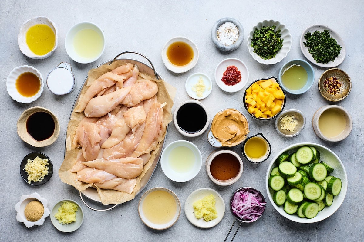 ingredients in bowls to make chicken satay with peanut sauce and cucumber mango salad.