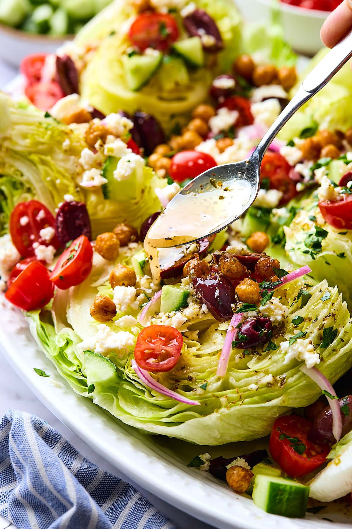 dressing being drizzled with a spoon over Greek wedge salad.