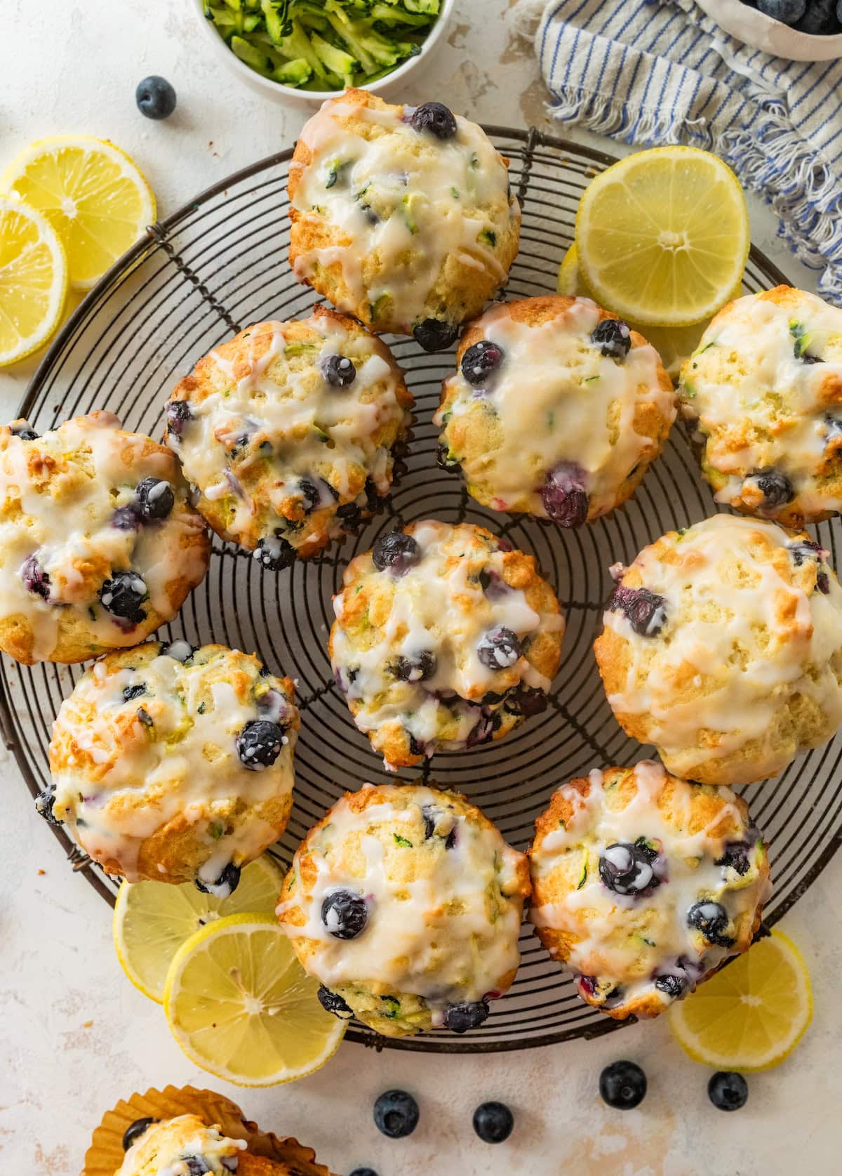 lemon blueberry zucchini muffins with lemon glaze on cooling rack.