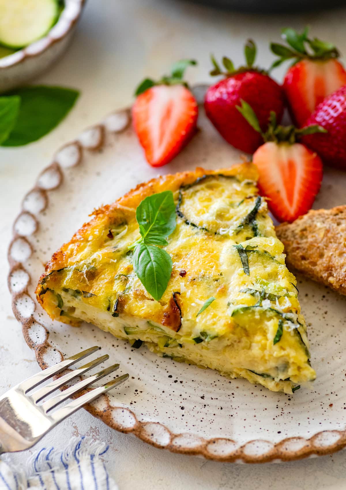 zucchini frittata on plate with strawberries.