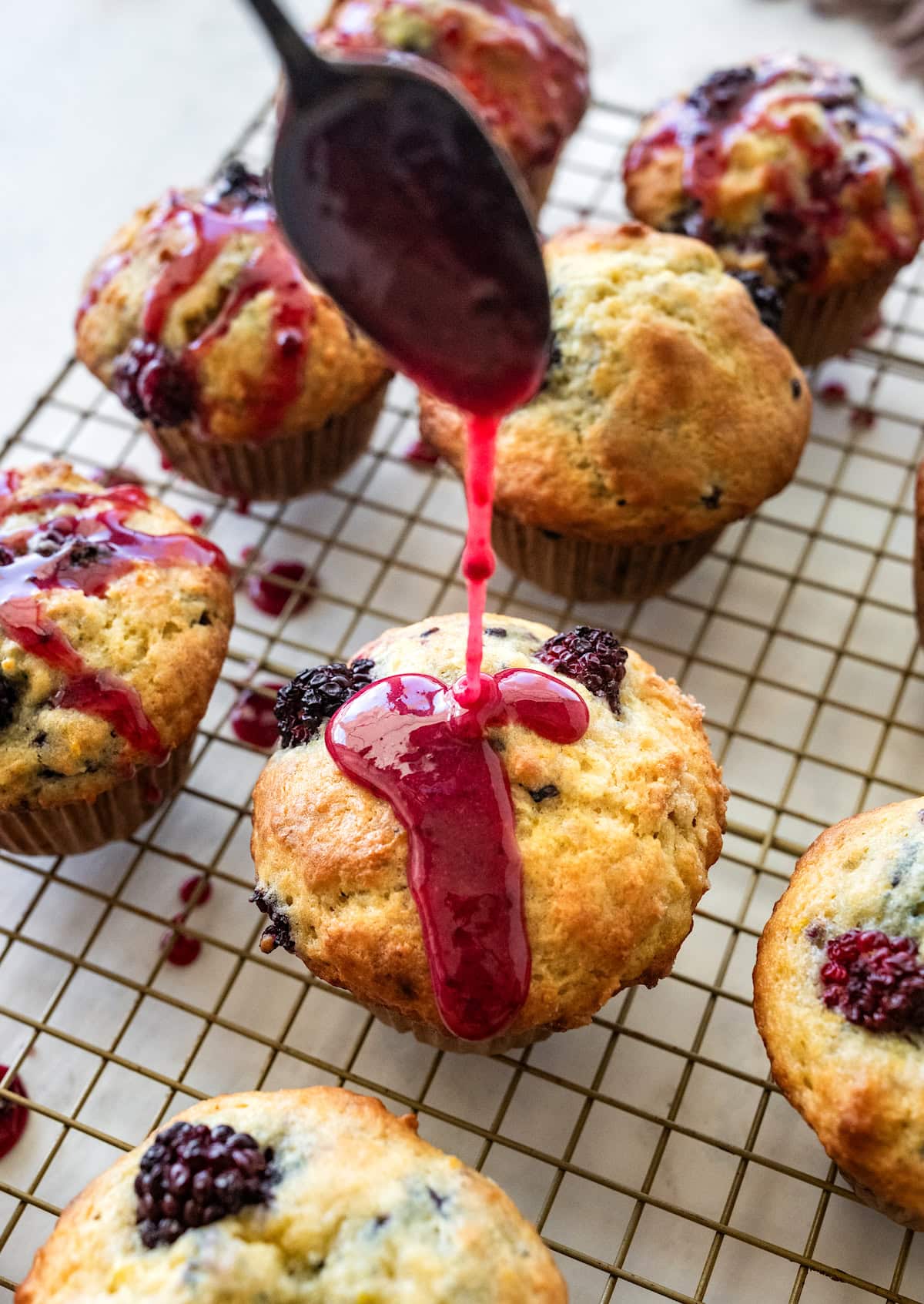 blackberry glaze being drizzled on soft blackberry muffin.