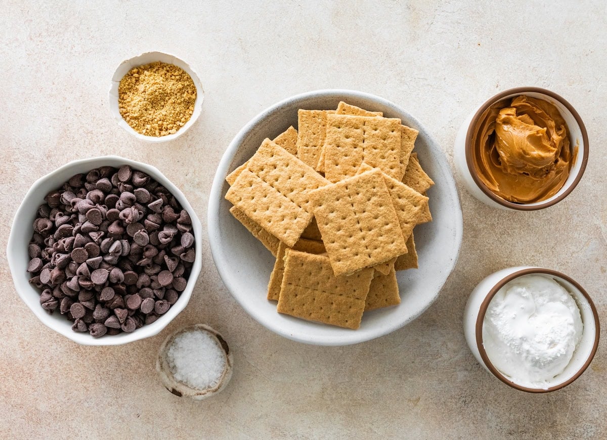 ingredients in bowls to make chocolate covered s'mores graham cracker sandwiches.