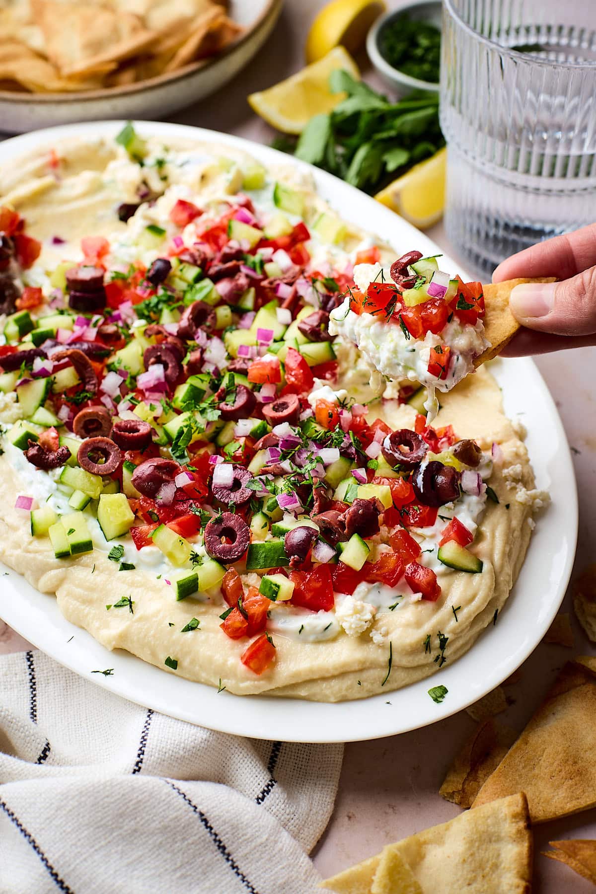 a pita chip being dipped into Greek layered dip.