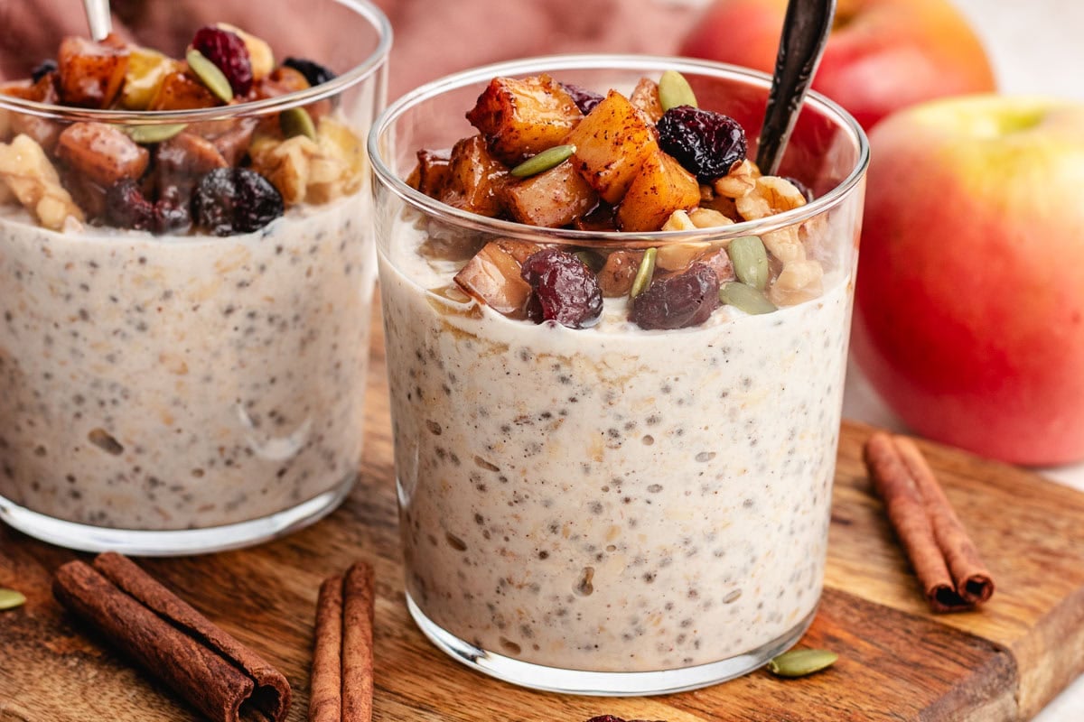 close up of apple pie overnight oats in glass cut with toppings and spoon.