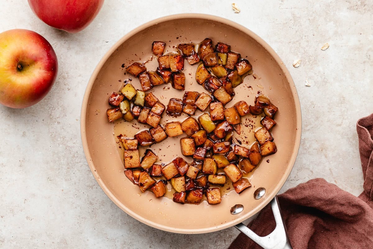 cinnamon maple chopped apples being cooked in skillet for apple pie overnight oats.