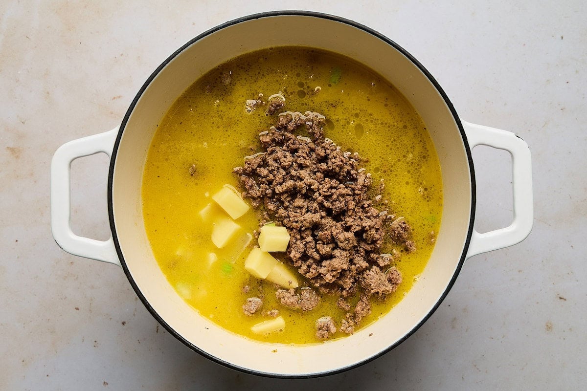 ground beef and potatoes being simmered in pot to make cheeseburger soup.