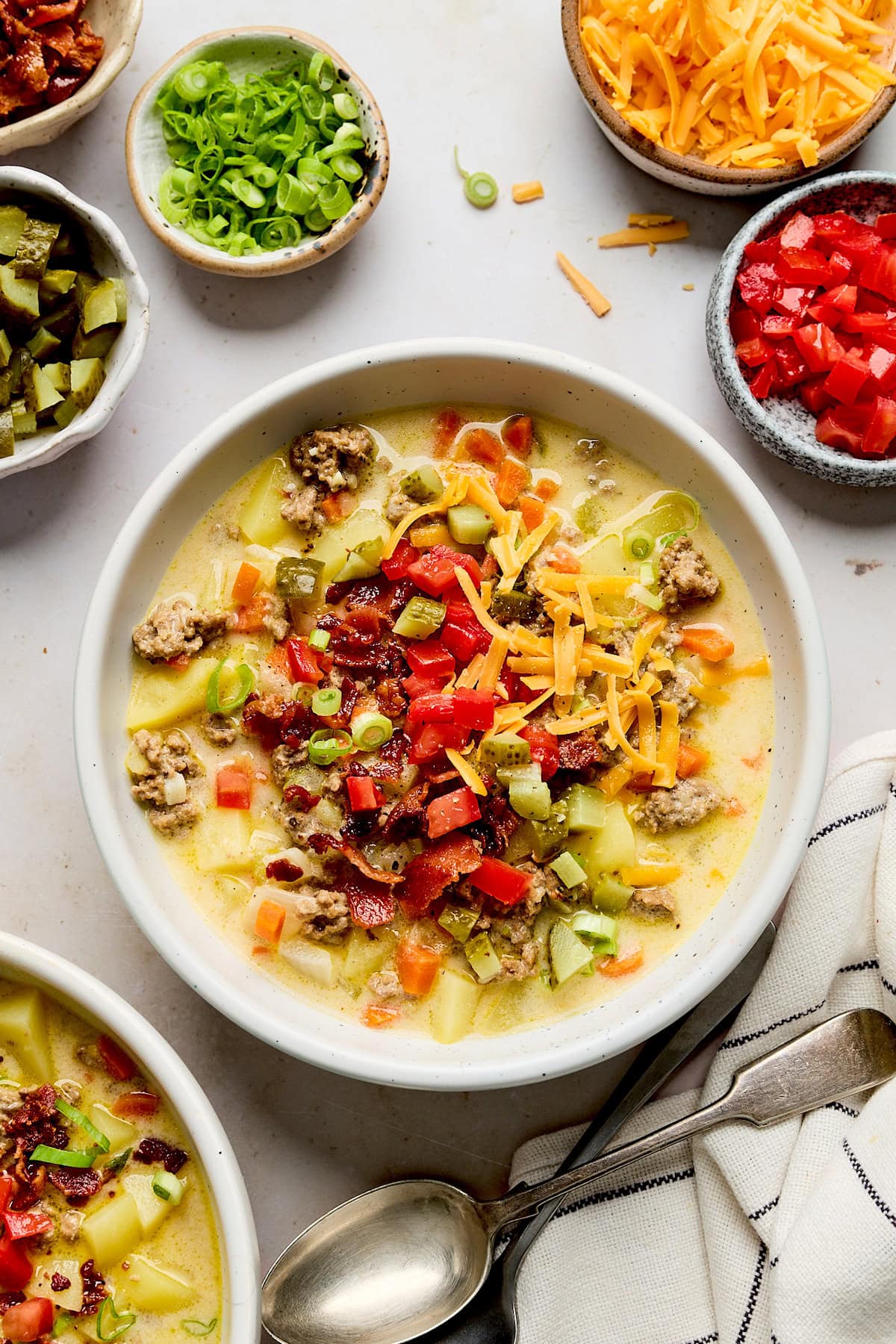 cheeseburger soup with bacon, cheese, green onion, and tomatoes in bowl.