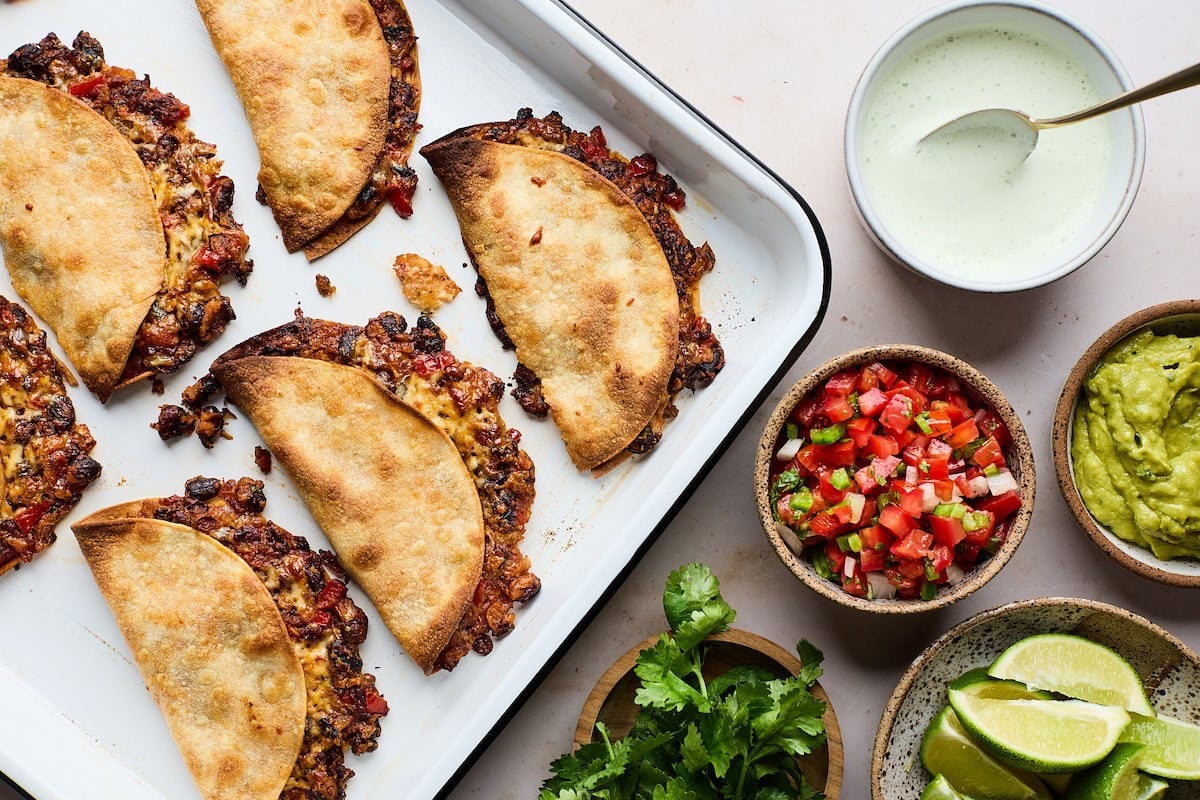 crispy black bean tacos on sheet pan with toppings.