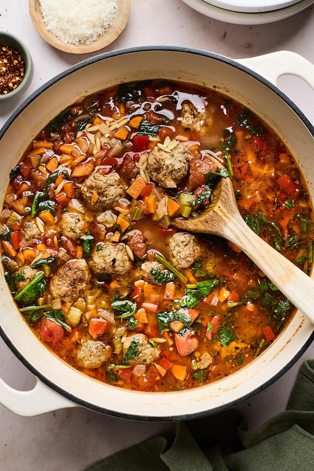 meatball orzo soup in pot with wooden serving spoon.