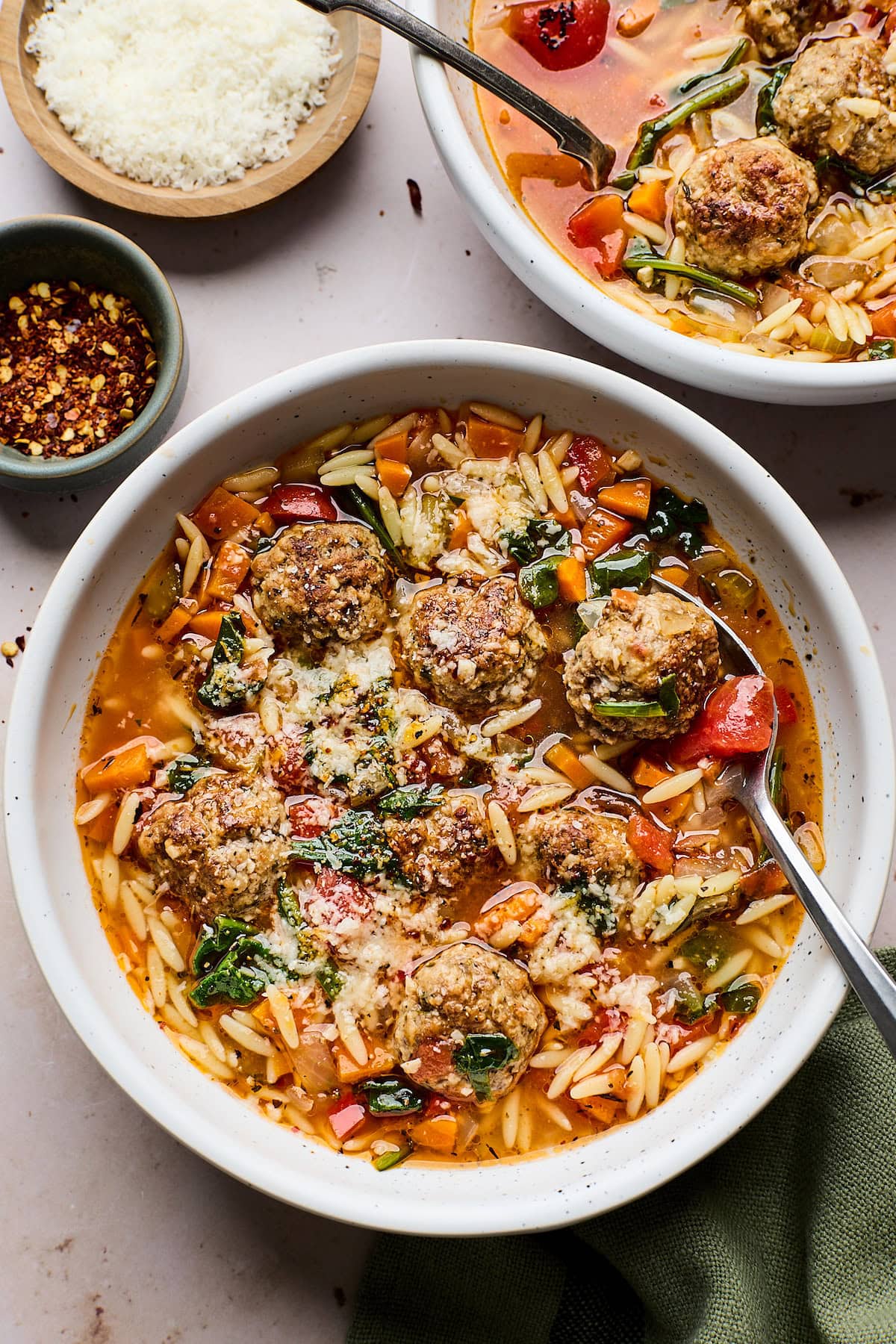meatball orzo soup with spinach and parmesan in bowl with spoon.