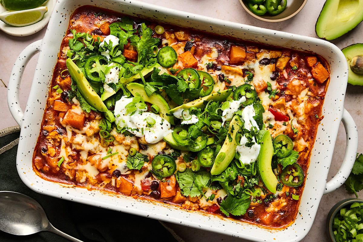 sweet potato chicken enchilada bake in pan with toppings.