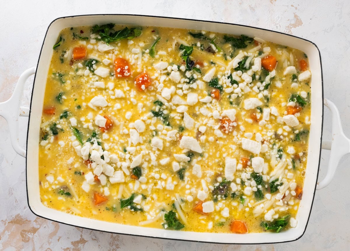 sweet potato kale breakfast casserole mixture in baking dish with crumbled feta on top.