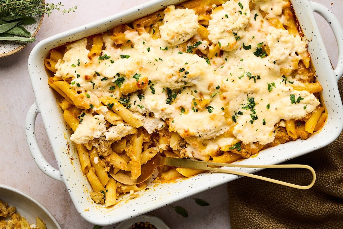 turkey pumpkin pasta bake in baking dish with serving spoon.